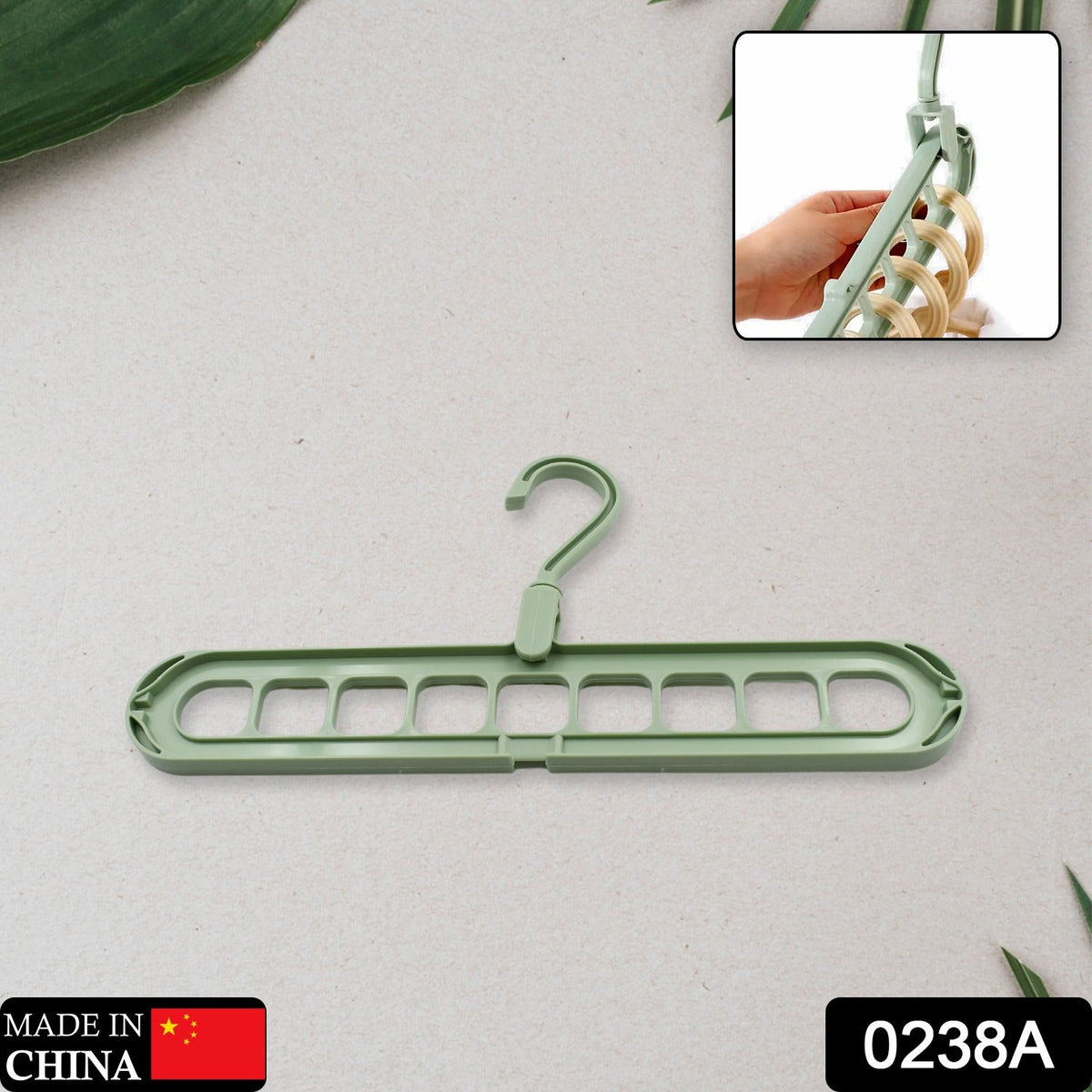 A green plastic multi-hole hanger on a gray background, with a hand holding it in the top right inset.