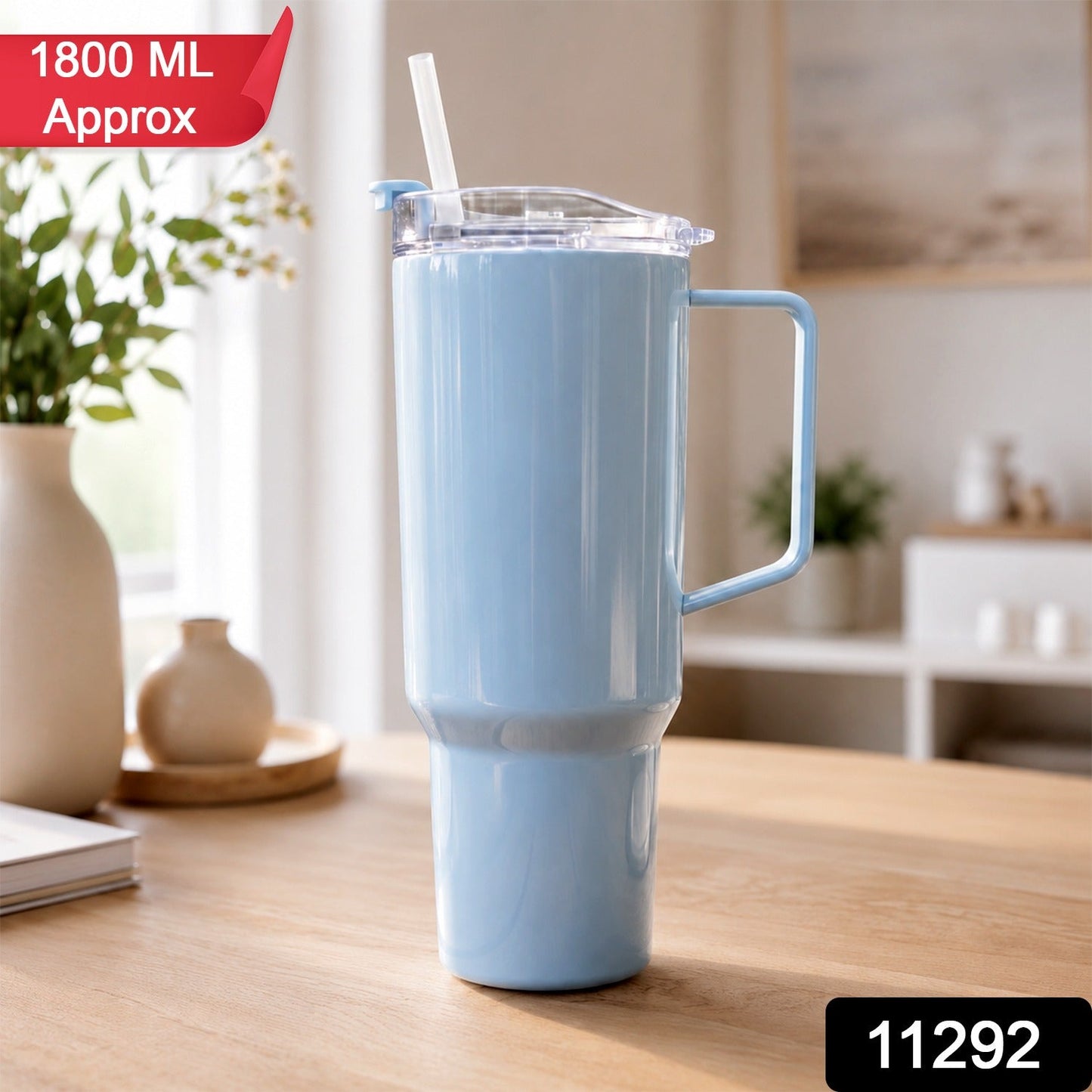 A light blue travel tumbler with a handle and straw sits on a wooden table, with