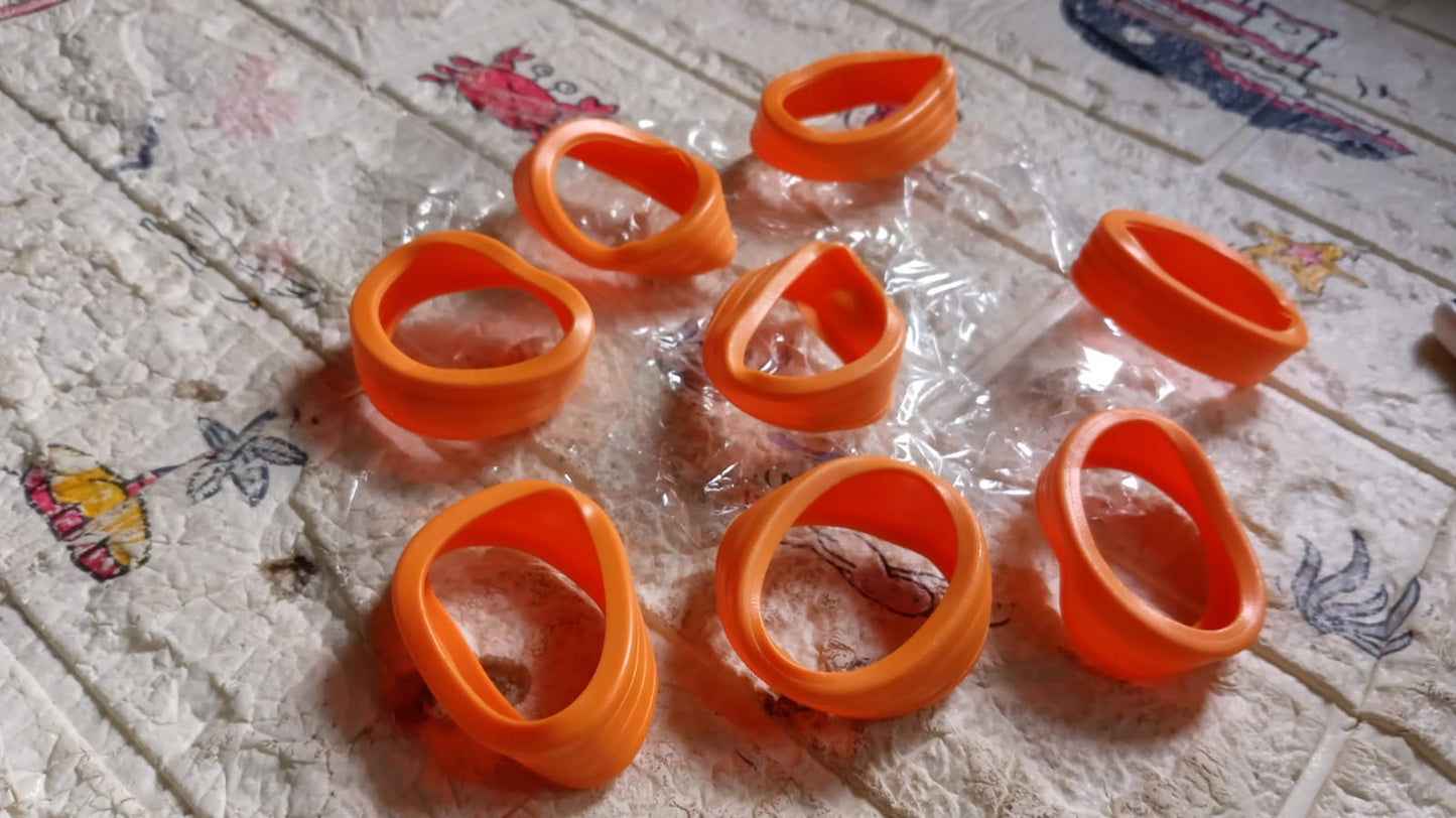 Eight orange silicone wheel covers scattered on a patterned, translucent surface, some with plastic packaging.