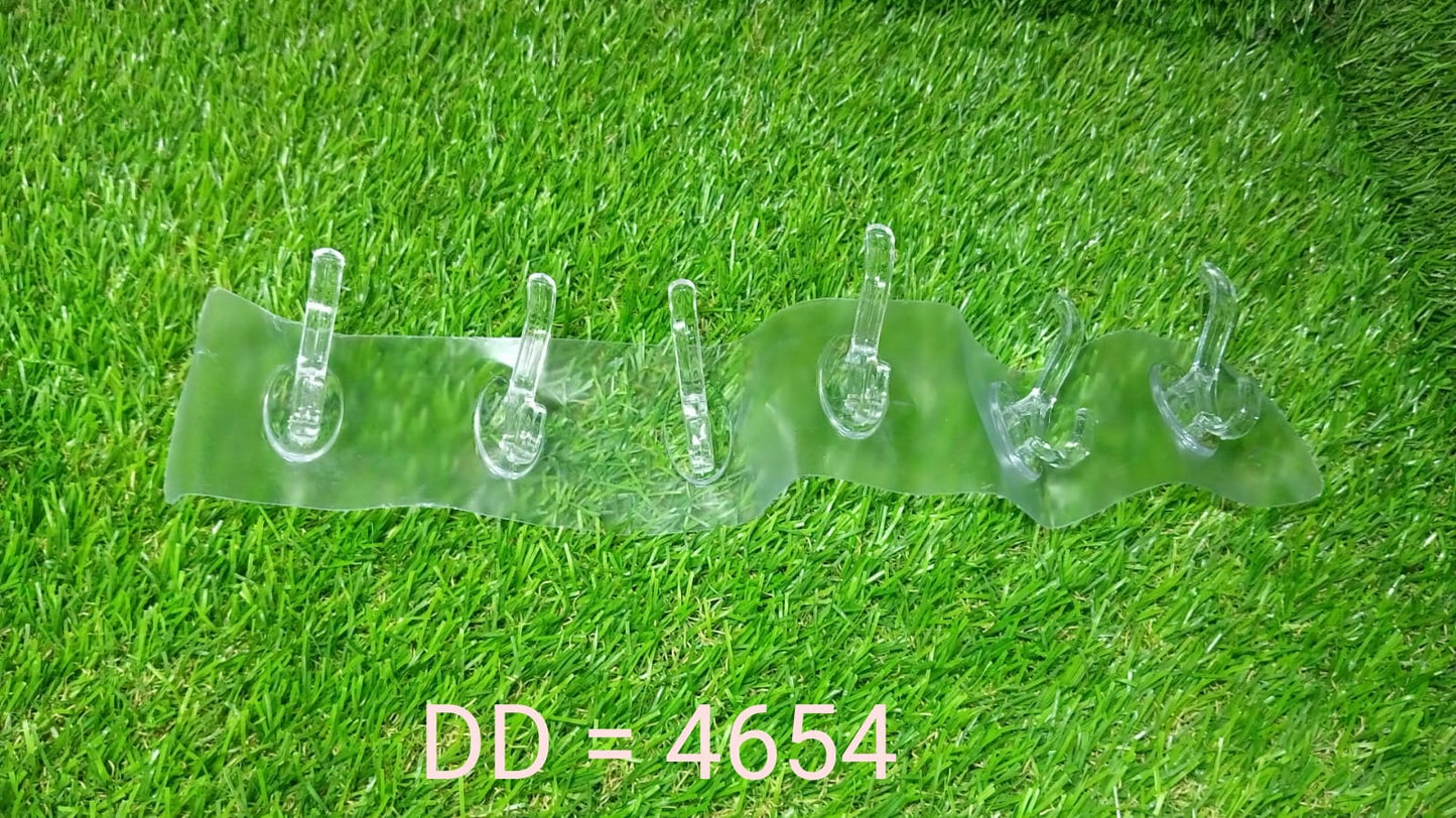A clear plastic 6-hook adhesive wall rail lies on vibrant green artificial grass.
