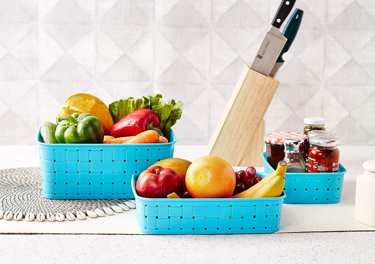 Three sky blue plastic storage baskets filled with fresh produce and jars in a kitchen setting.