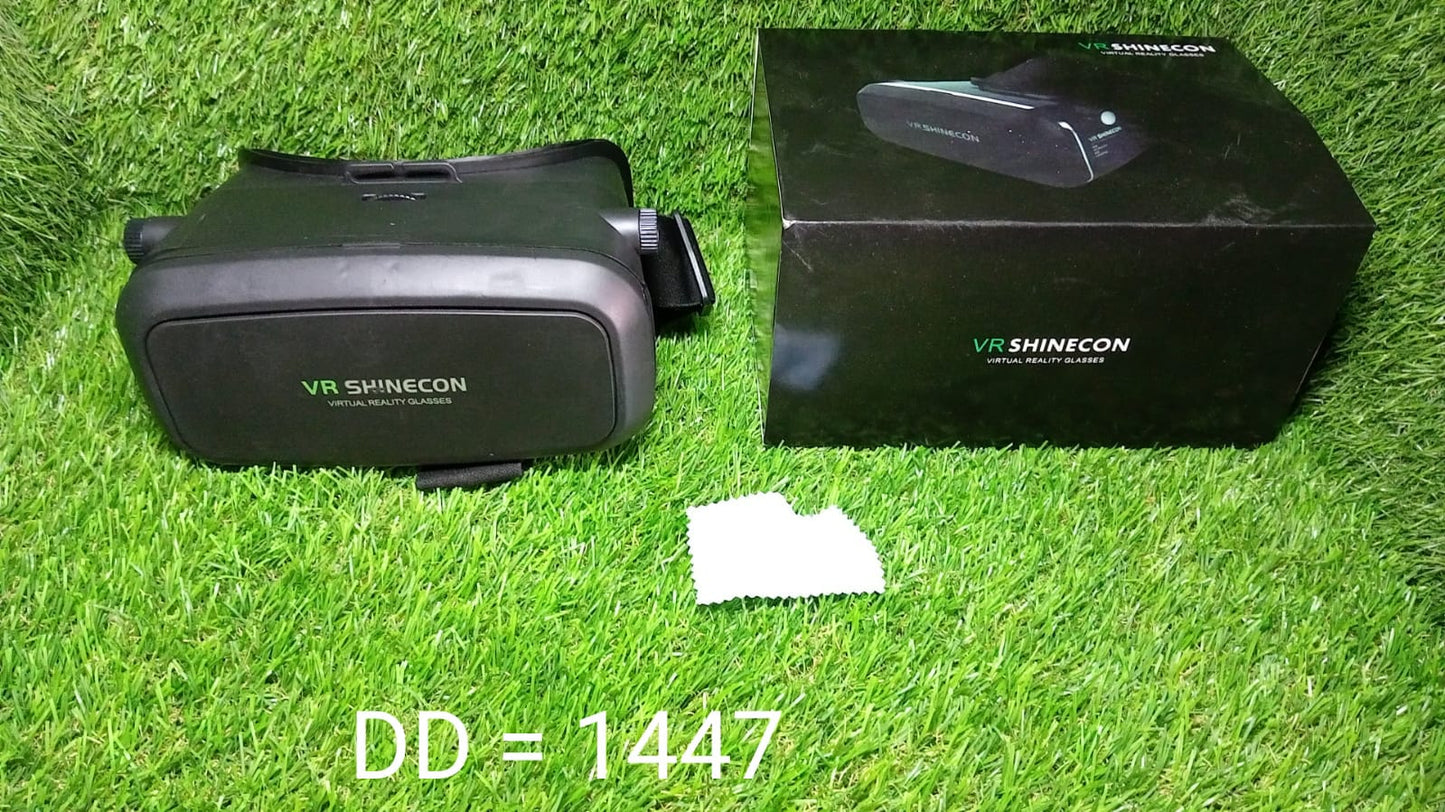 A black VR headset and its matching box with green text are placed on a vibrant green grass surface, with a small white