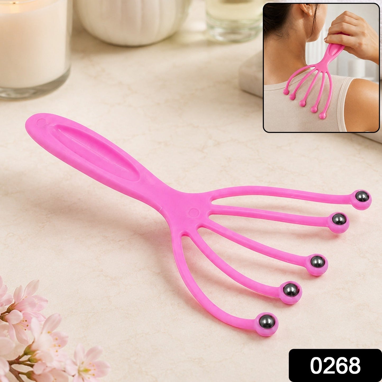 A pink plastic scalp massager with five flexible arms ending in metal roller balls, with a small black box containing the