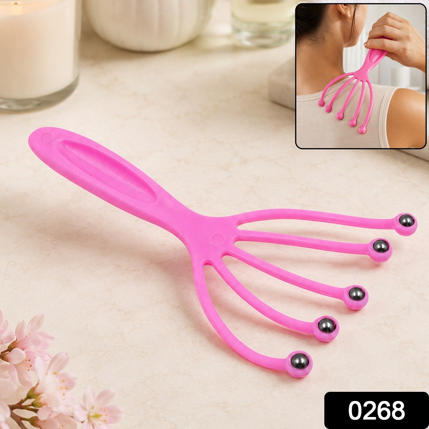 A pink plastic scalp massager with five flexible arms ending in metal roller balls, with a small black box containing the