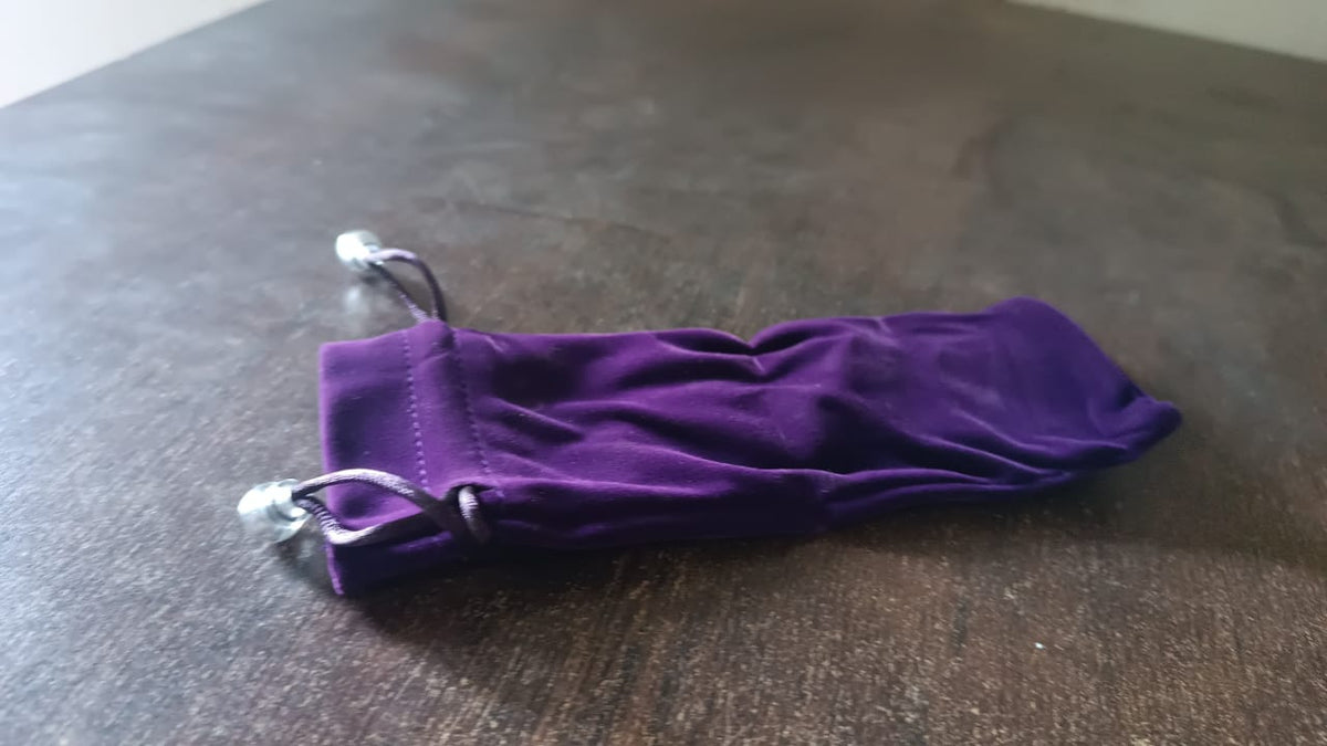 A purple velvet drawstring bag with a DayShow logo lies on a dark brown wooden surface.