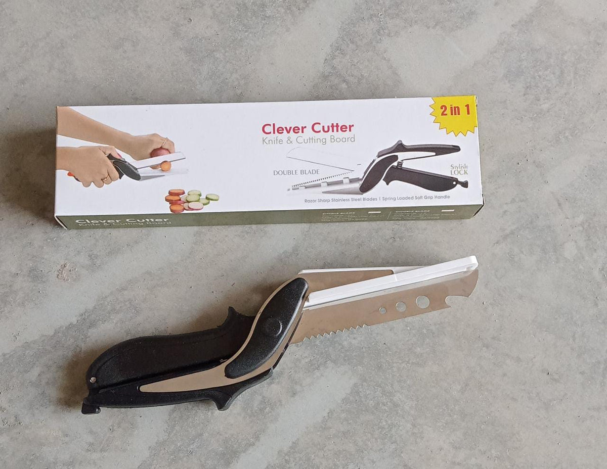 A black and white clever cutter with its product packaging is shown on a light gray concrete surface.