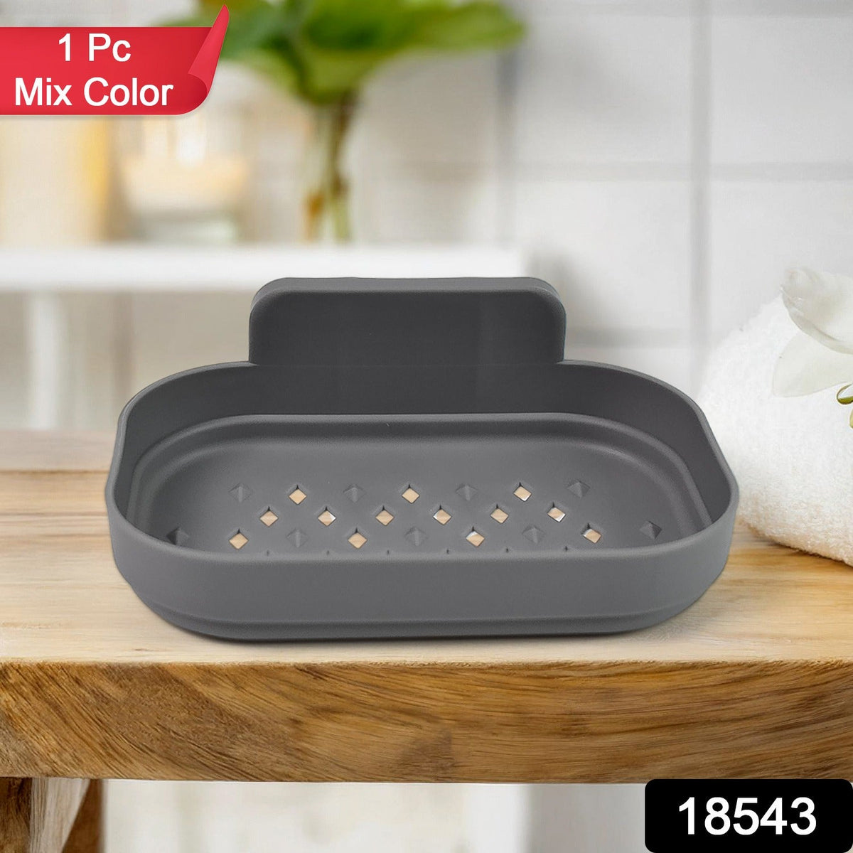 A gray self-adhesive soap dish with drainage holes sits on a wooden counter in a bathroom setting.