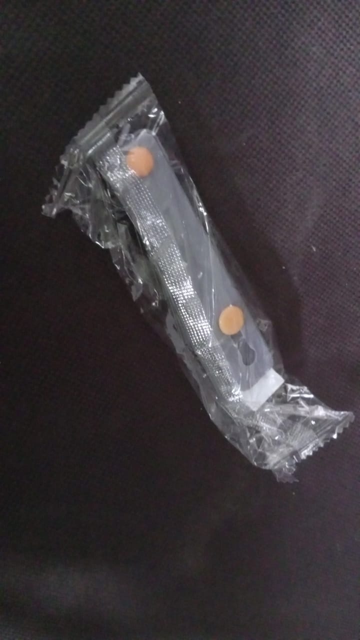 A single dark gray silicone phone grip with orange buttons, sealed in clear plastic packaging on a dark background.