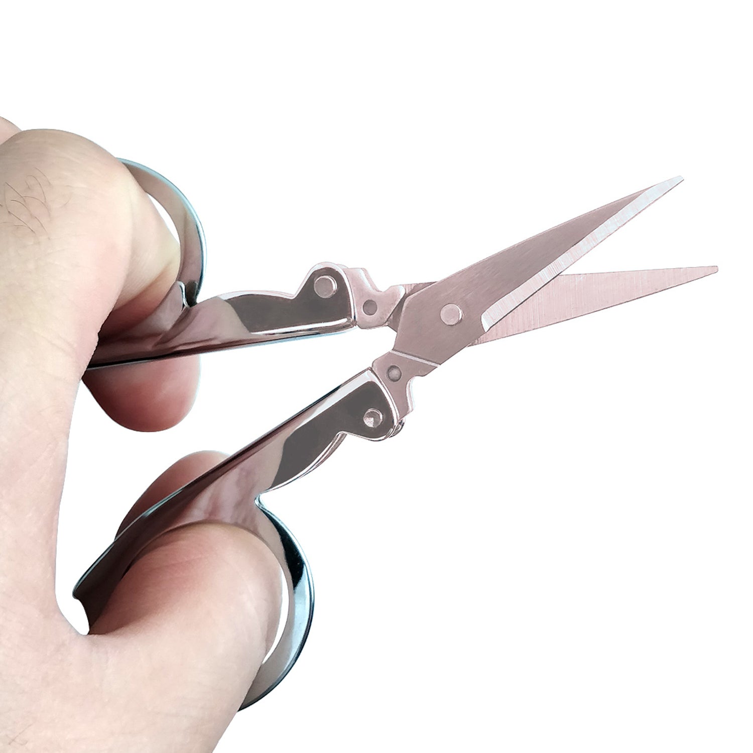 A hand holds open silver folding scissors against a white background.