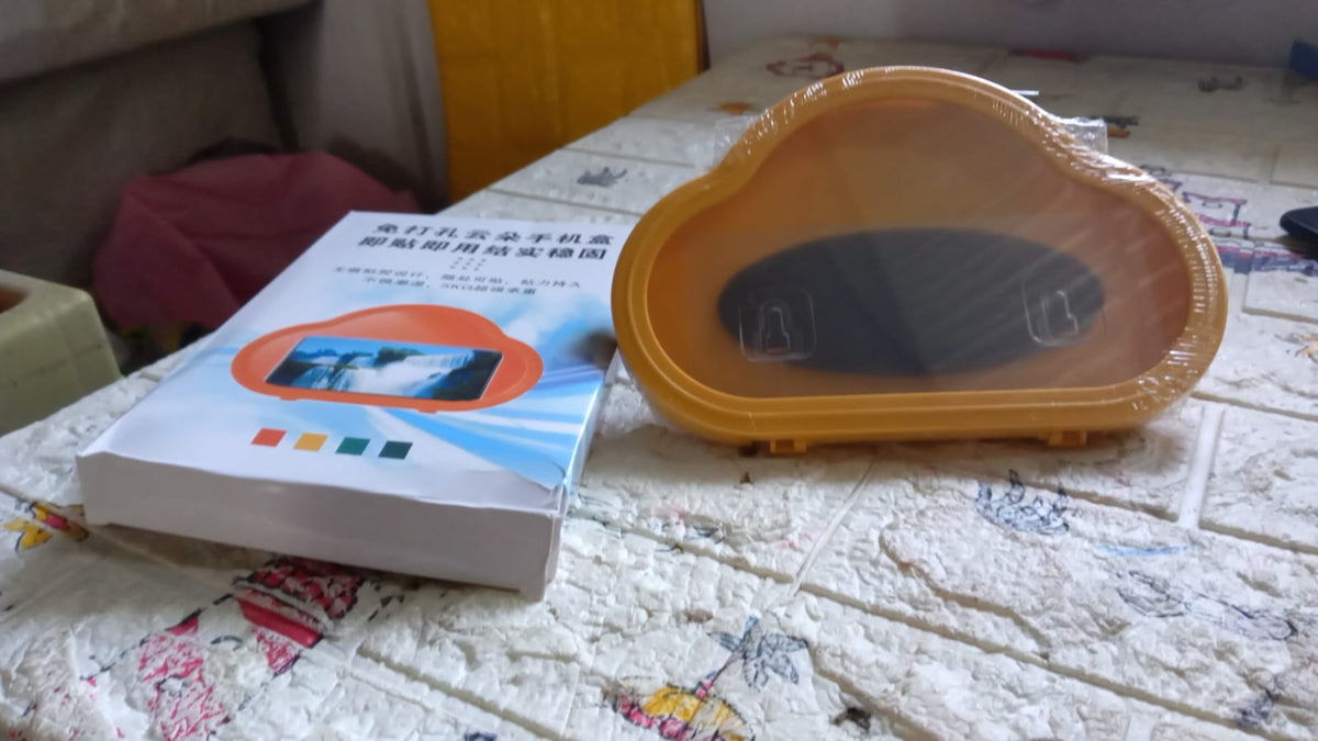 A yellow cloud-shaped phone holder and its white instruction manual on a textured surface.