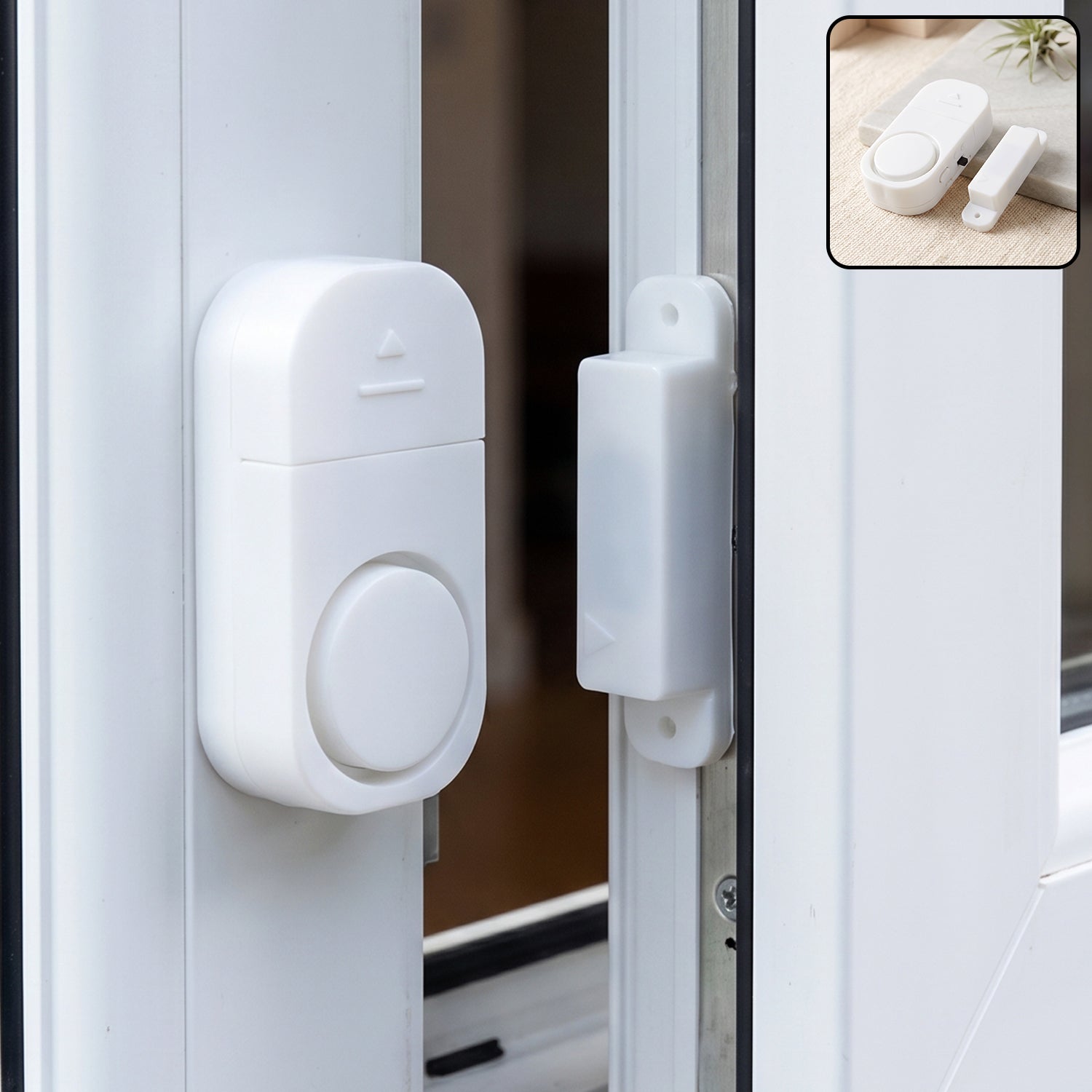 A white magnetic door and window security alarm is installed on a white window frame, with the two pieces separated.