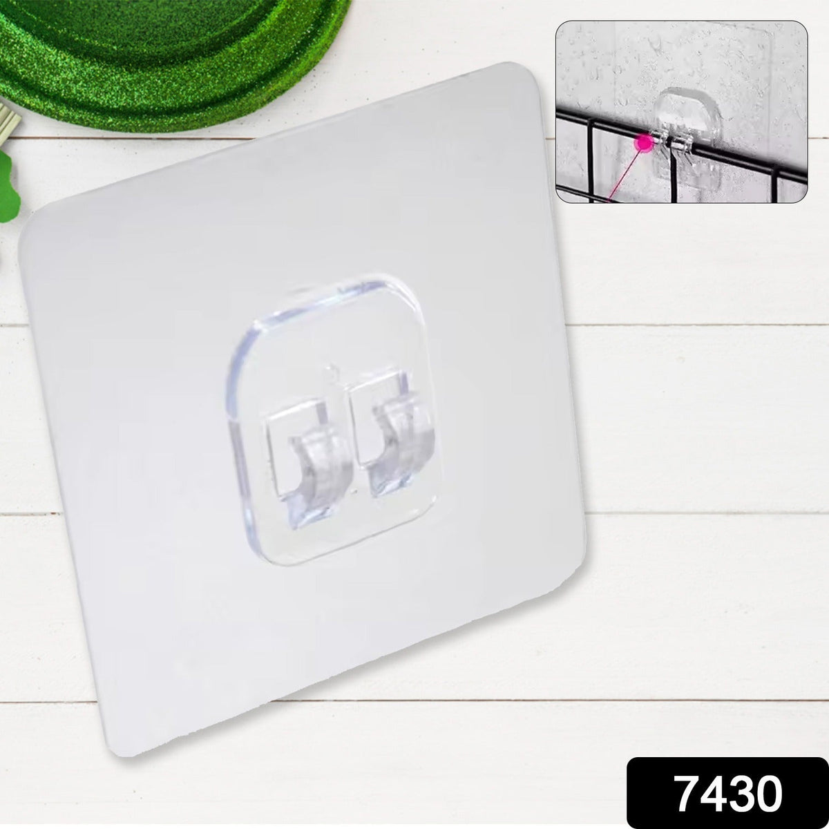 A clear self-adhesive wall hook is shown on a white wooden surface with a small inset image of the hook in use.
