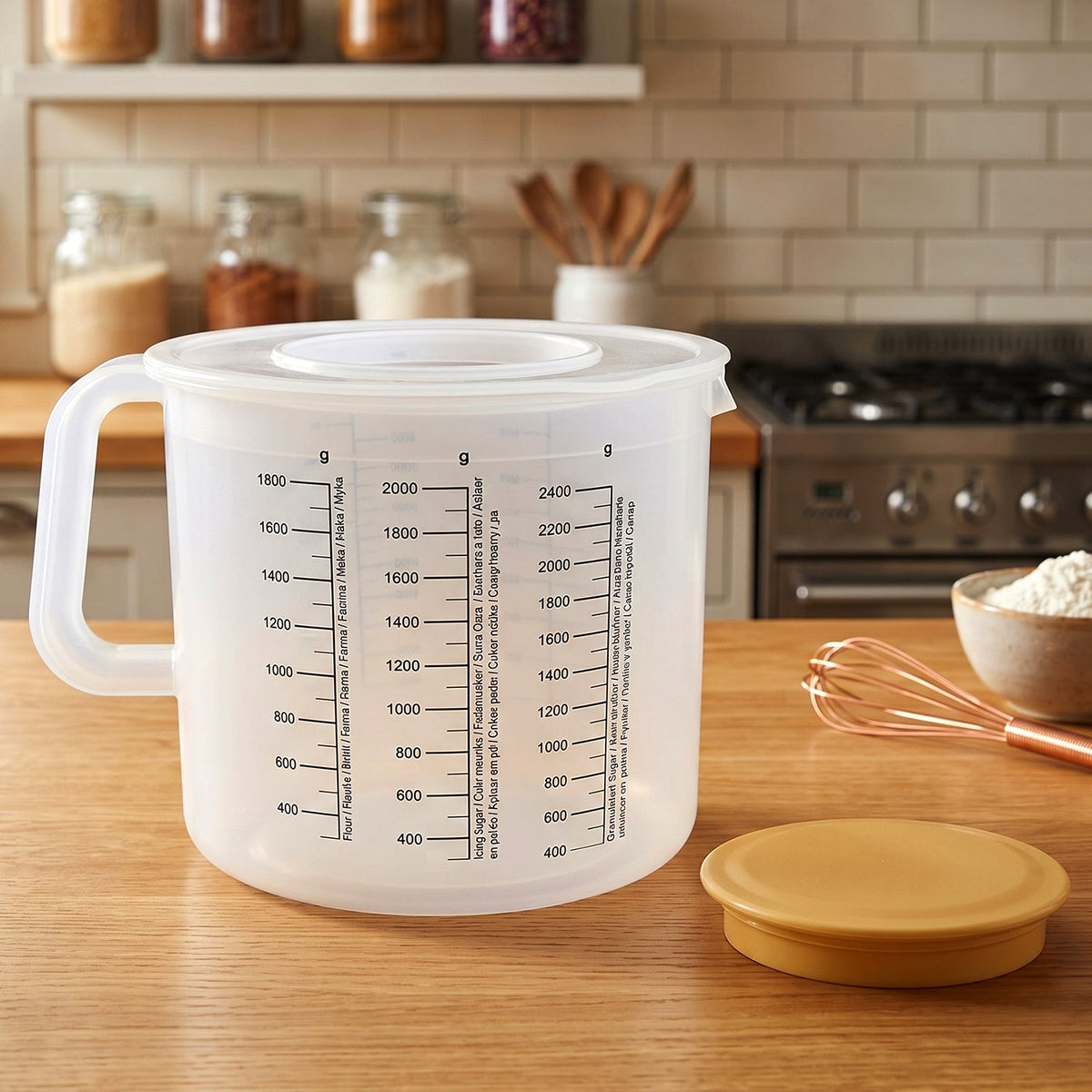 A clear plastic measuring jug with its yellow lid removed, sitting on a wooden kitchen counter.