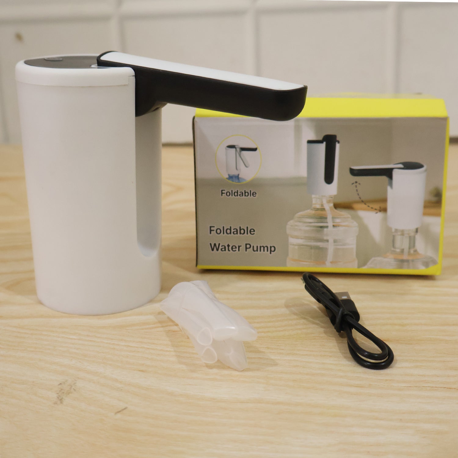 The white and black electric water dispenser pump, a clear silicone tube, and a black USB charging cable are displayed next