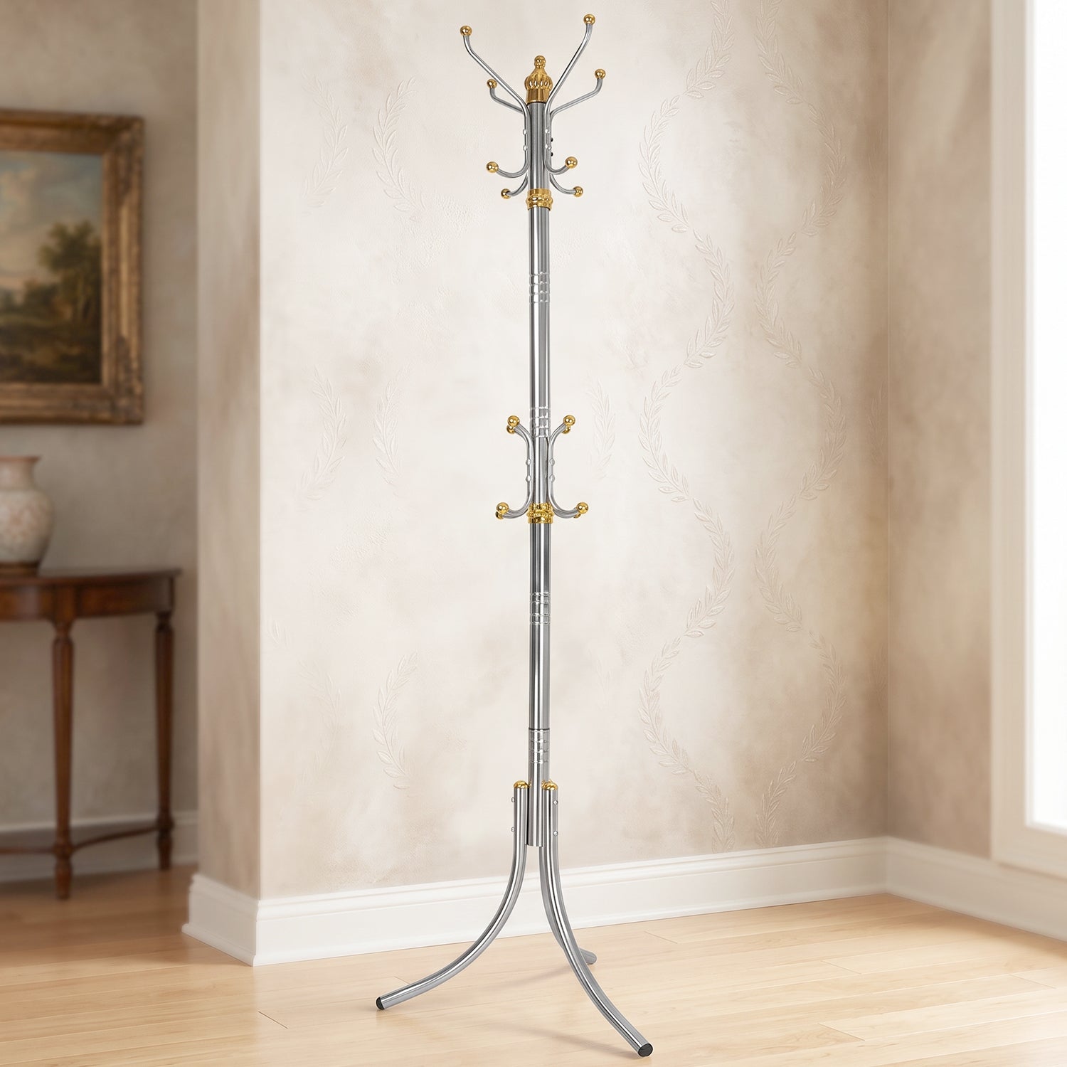 A tall, silver-colored metal clothes hanger stand with gold accents and multiple hooks stands in a room with patterned