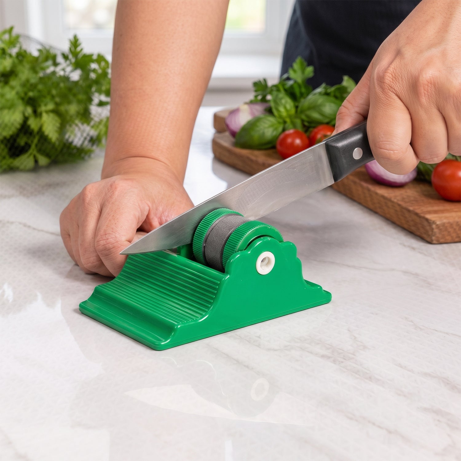 A person sharpens a knife on a green compact sharpener on a white marble counter, with vegetables in the background.