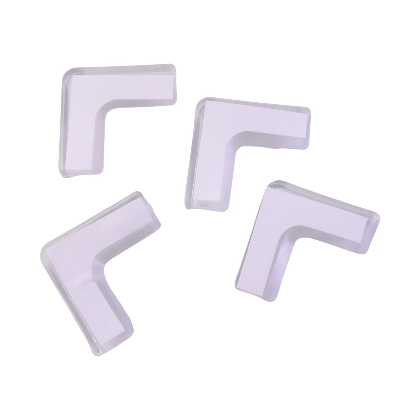Four clear silicone corner protectors with white adhesive backing are scattered on a plain white background.