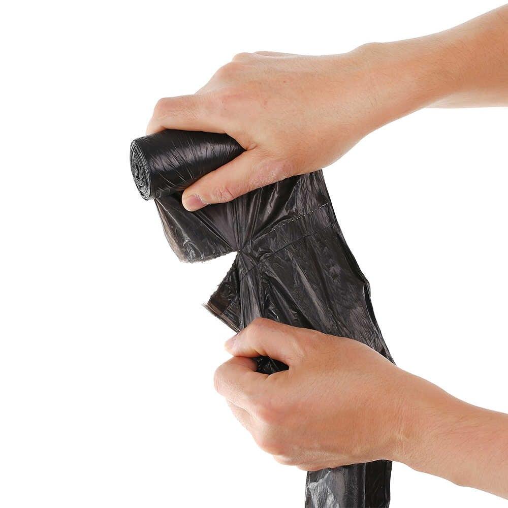 Hands unrolling and tearing off a single black garbage bag from a roll.