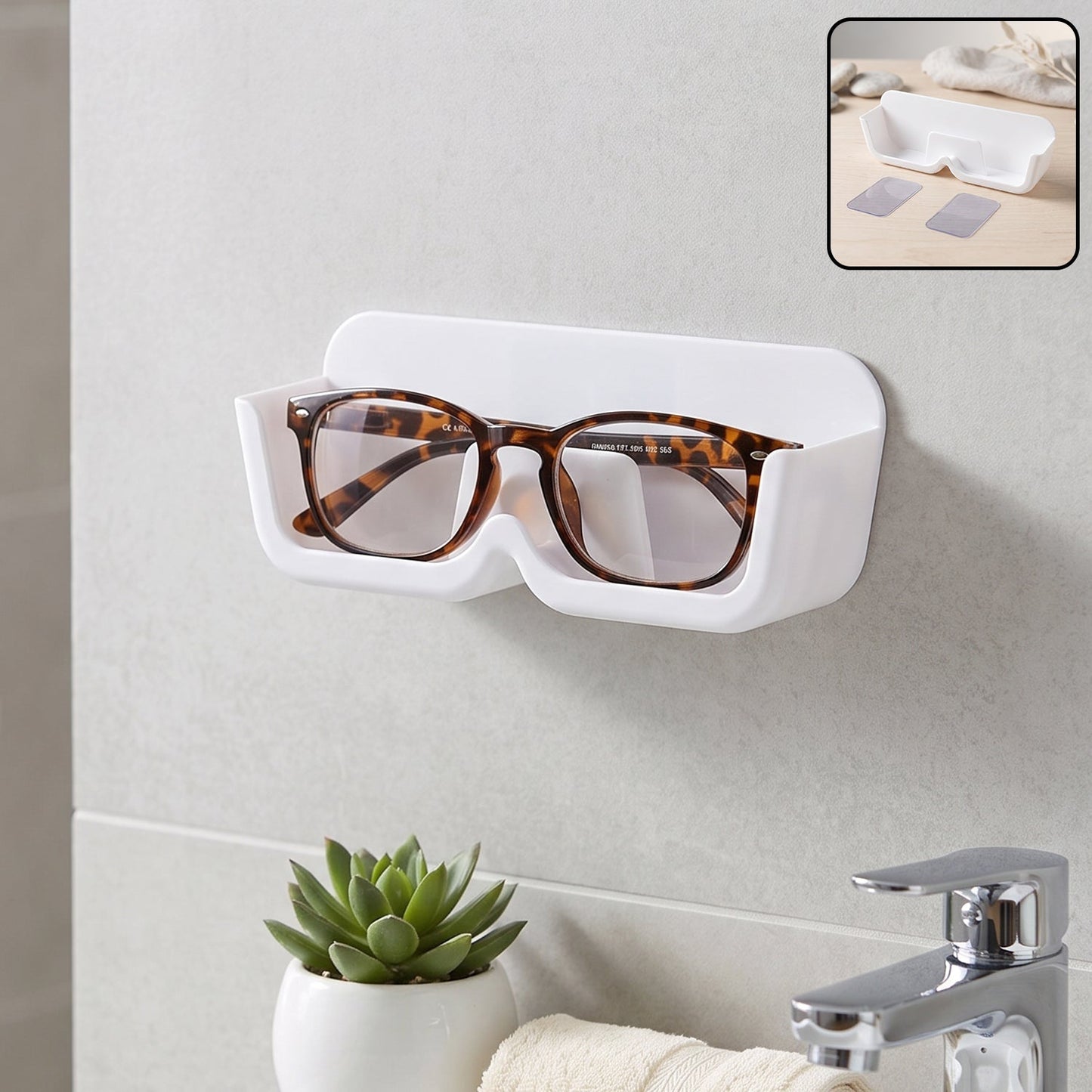 White plastic wall-mounted eyewear holder with tortoise-shell glasses, above a sink with a small green plant