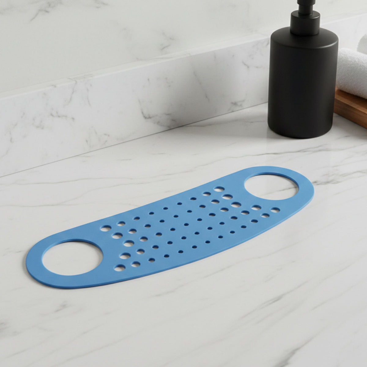 The blue silicone perforated strap rests on a white marble countertop next to a black soap dispenser.