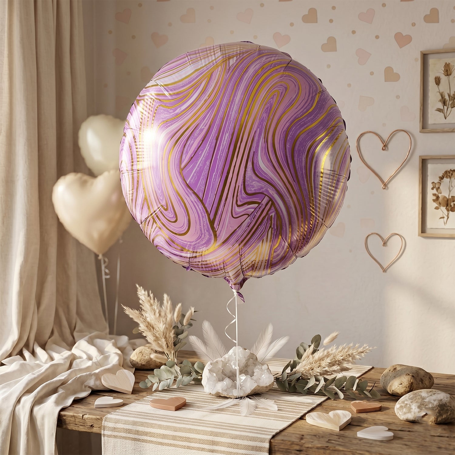 A purple and gold marble foil balloon floats above a rustic table decorated with pampas grass and heart-shaped accents.