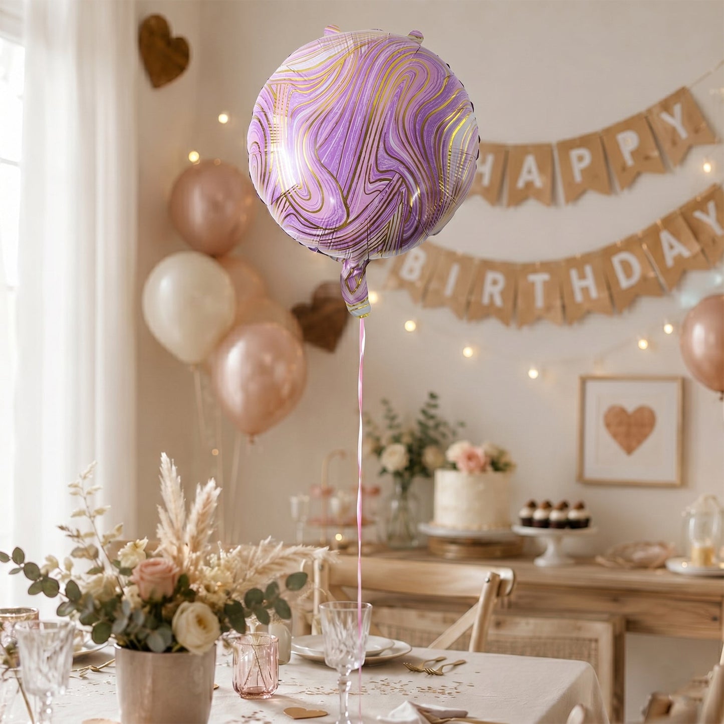 A purple and gold marble foil balloon floats in a room decorated for a birthday party with a banner and balloons.