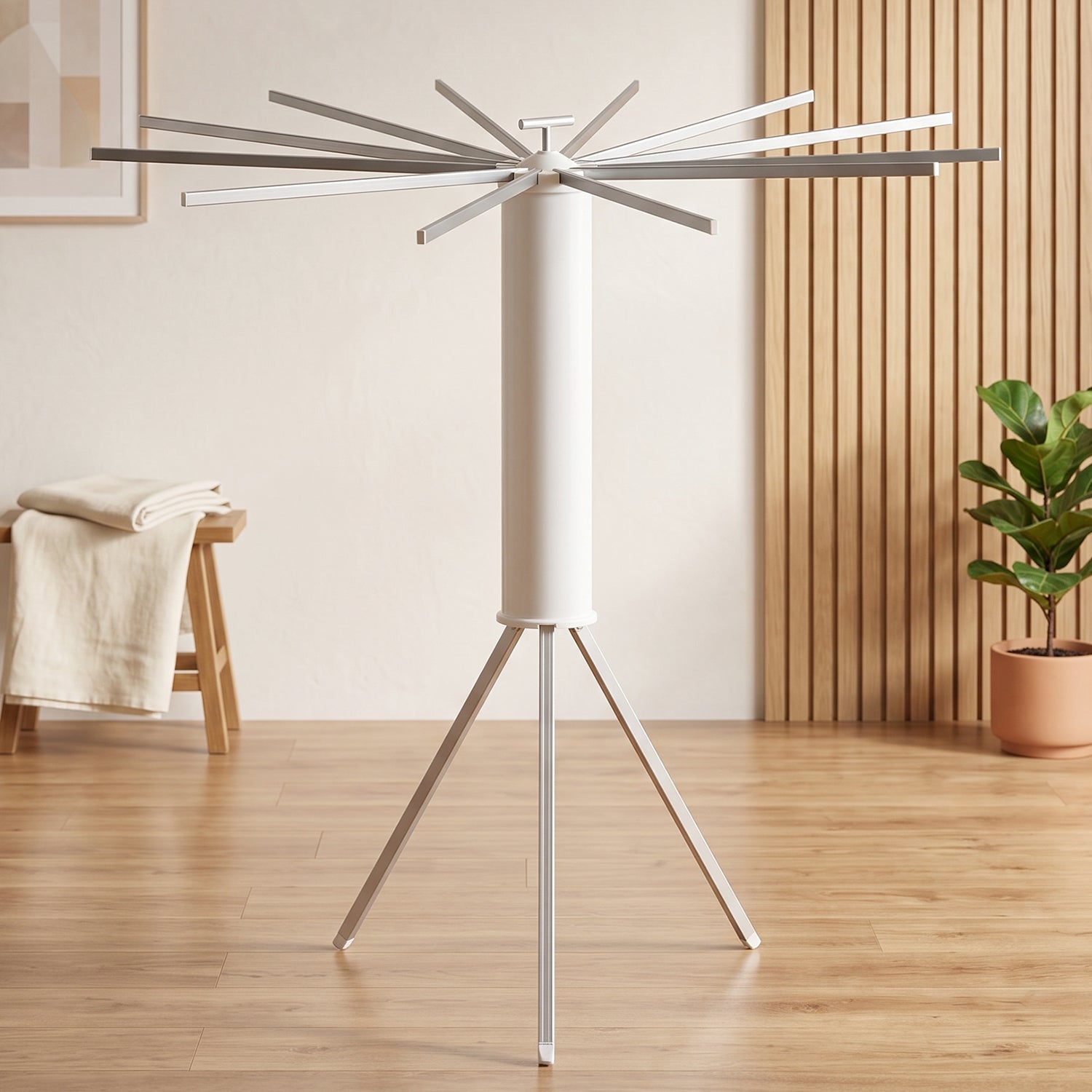 White tripod clothes drying rack with all arms extended, in a room with wooden floors and a plant.