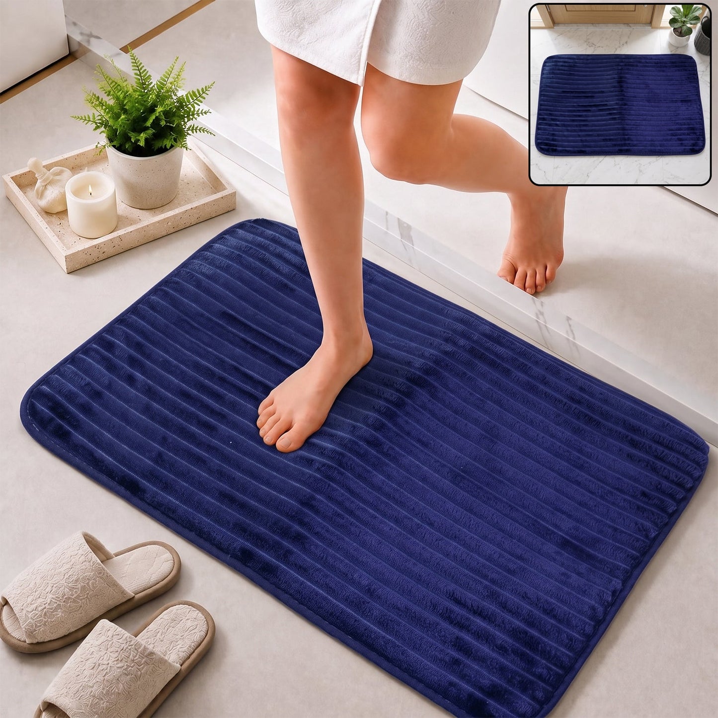 A person steps onto a navy blue ribbed memory foam bath mat from a shower, with slippers nearby.