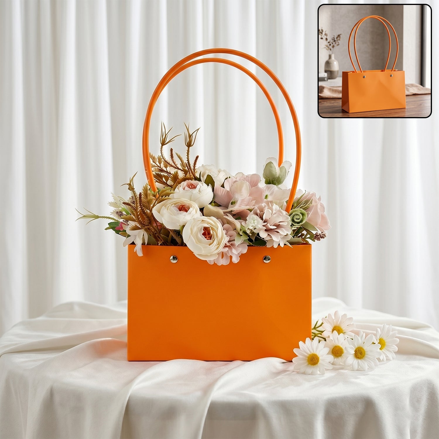 An orange rectangular gift bag with round handles, filled with an assortment of light-colored artificial flowers, sits on a