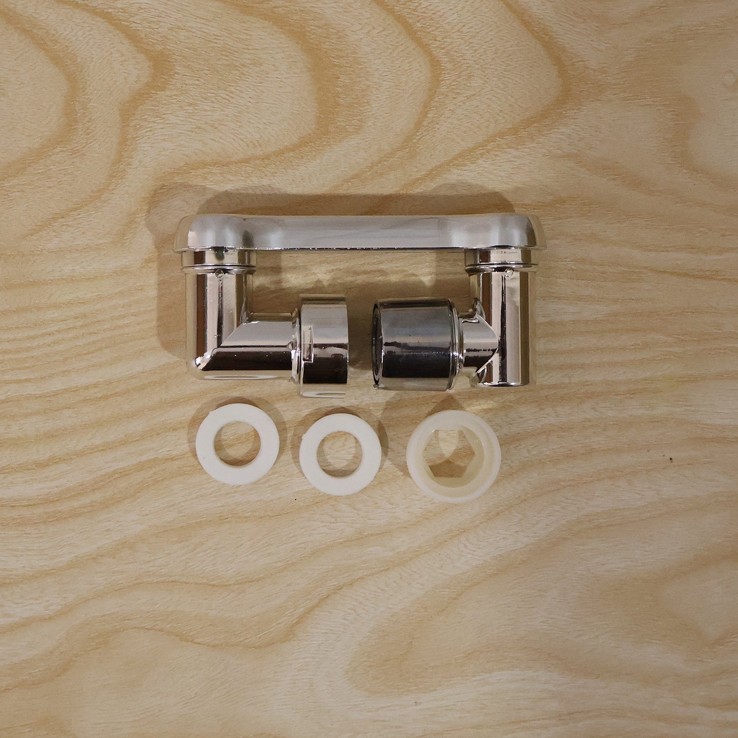 The chrome rotatable faucet splash head extension is shown in two pieces with three white washers on a light wooden surface.