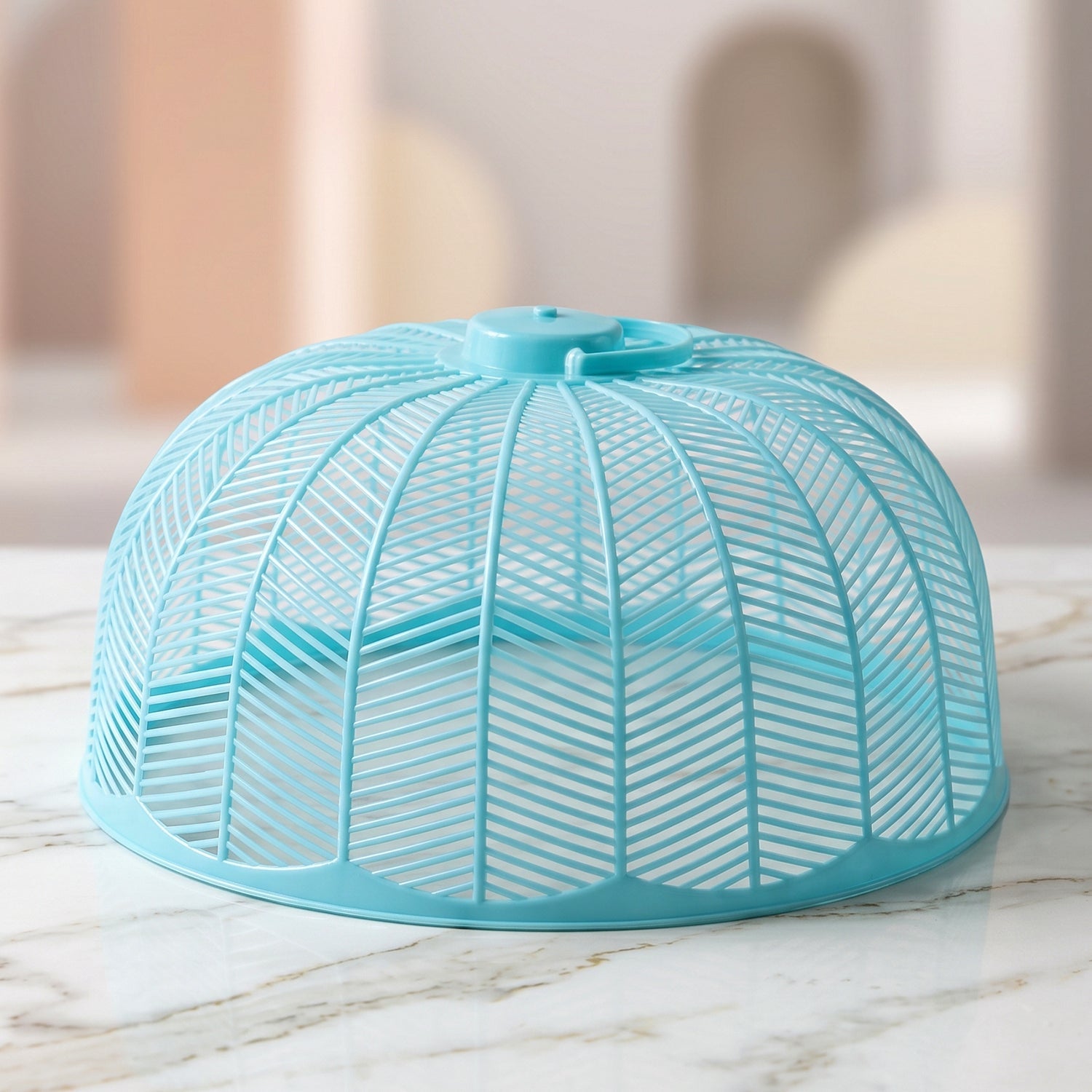 Close-up of a light blue plastic mesh food cover dome on a marble surface.