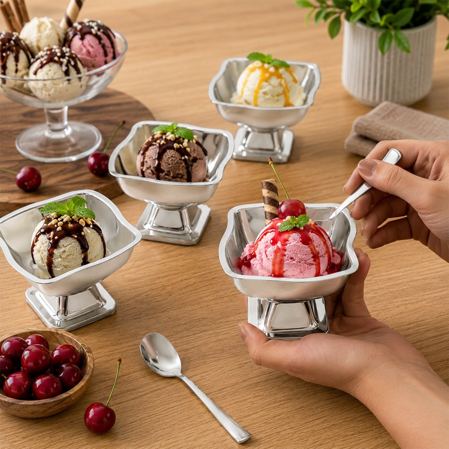 Five stainless steel ice cream cups with various ice cream flavors, a hand holding one cup with a spoon.