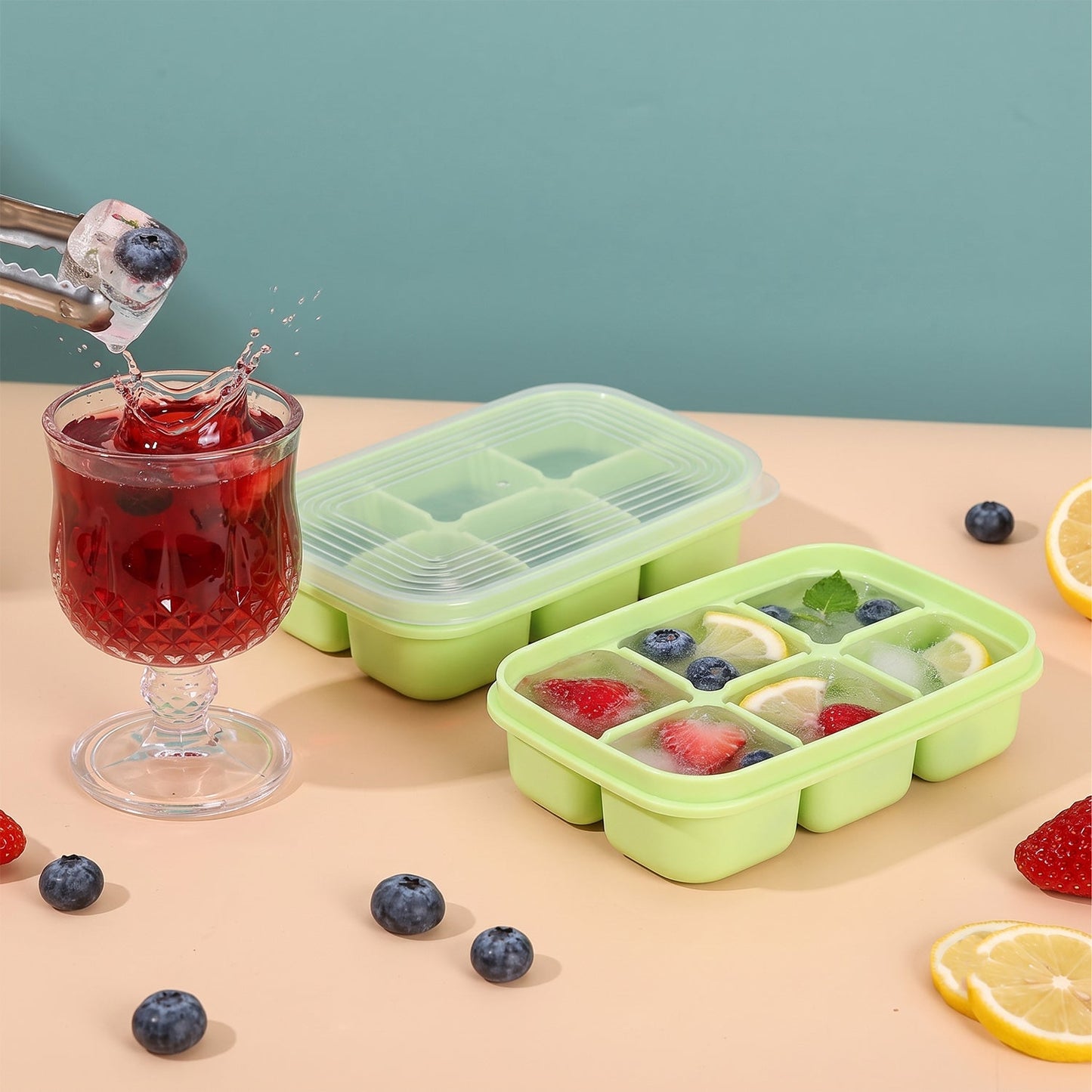 Two green 6-cavity ice cube trays, one with a clear lid, next to a glass of red drink with an ice cube being dropped in,