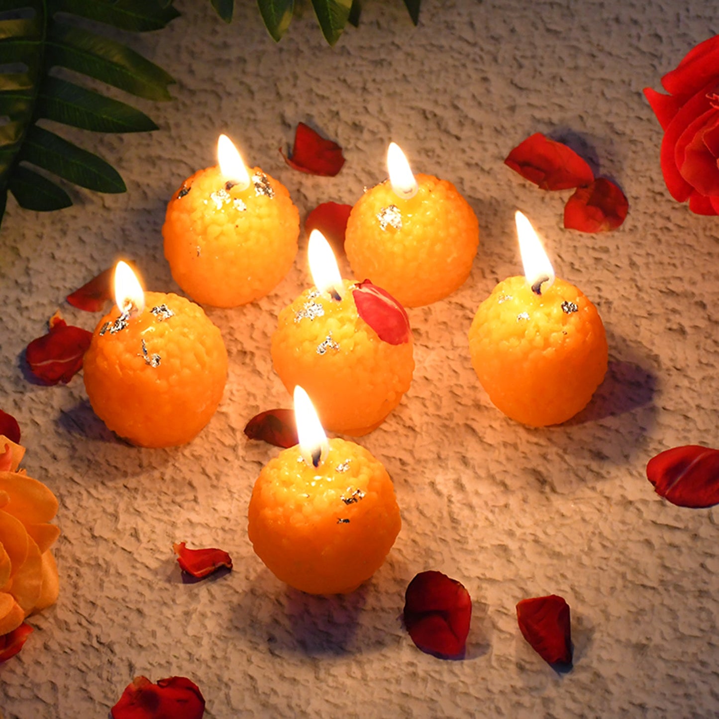 Orange laddu shaped wax candles with slow-burning wicks and silver leaf accents