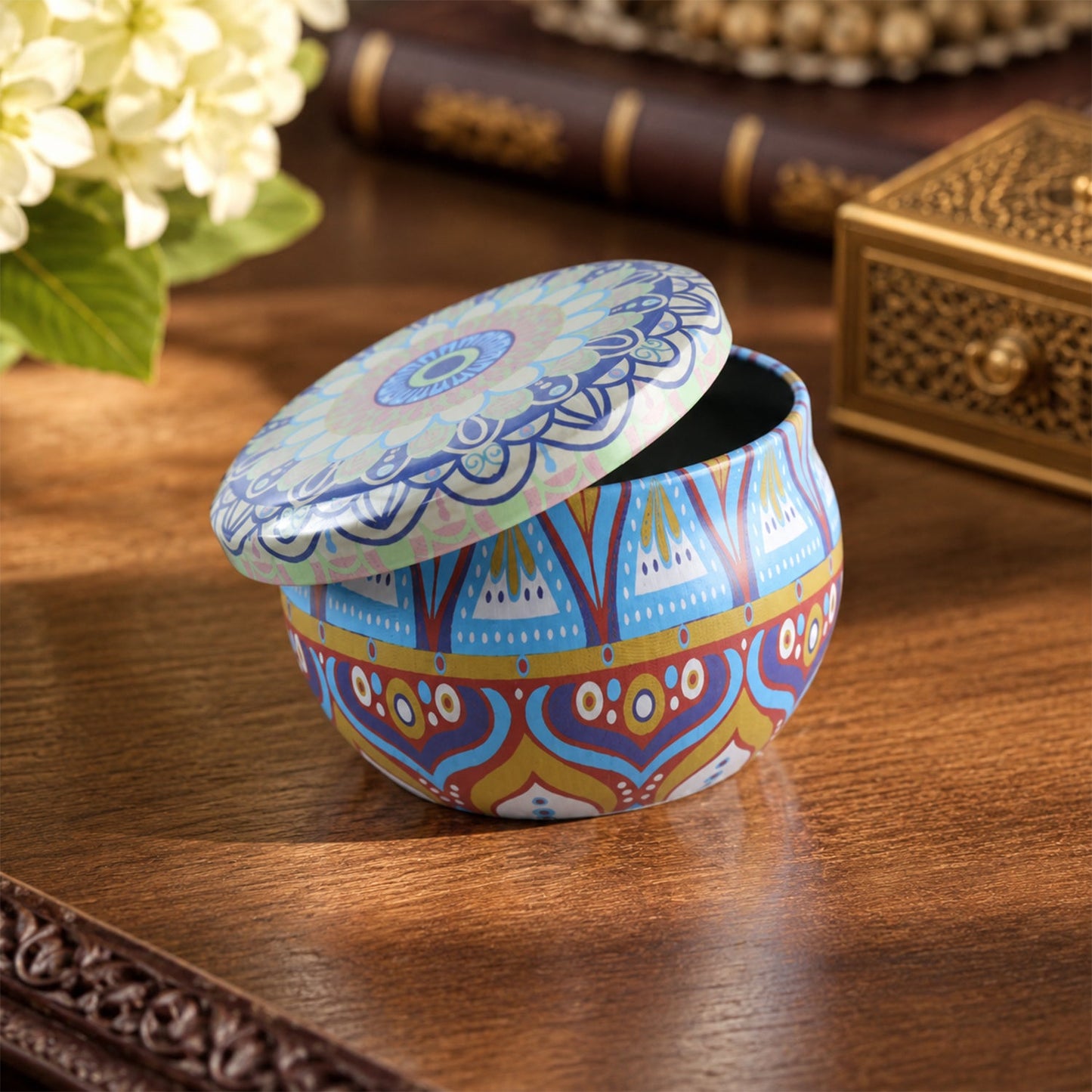 A colorful mandala tin box with its lid slightly ajar, sitting on a dark wooden table with blurred decor.