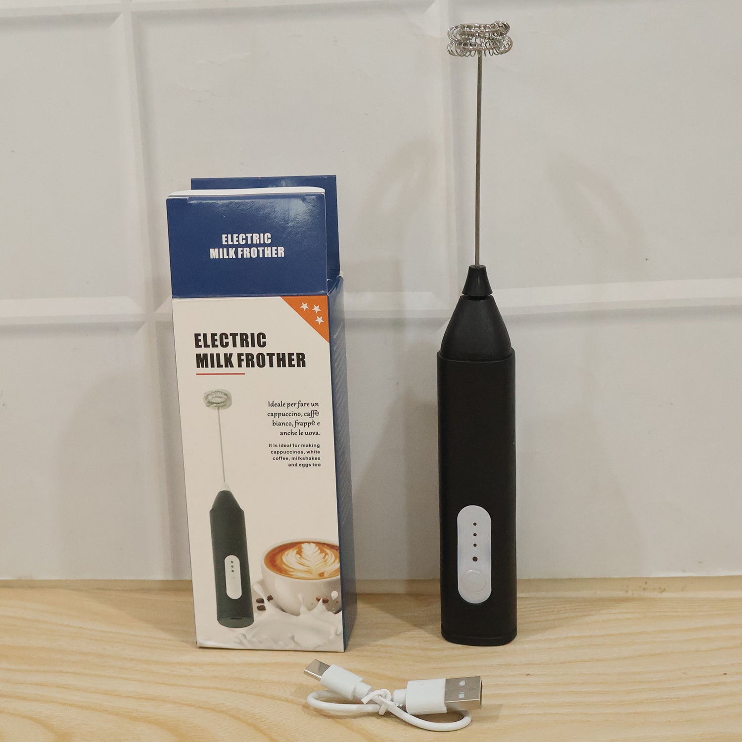 A black handheld electric milk frother and its blue and white product box are displayed with a white USB charging cable (1