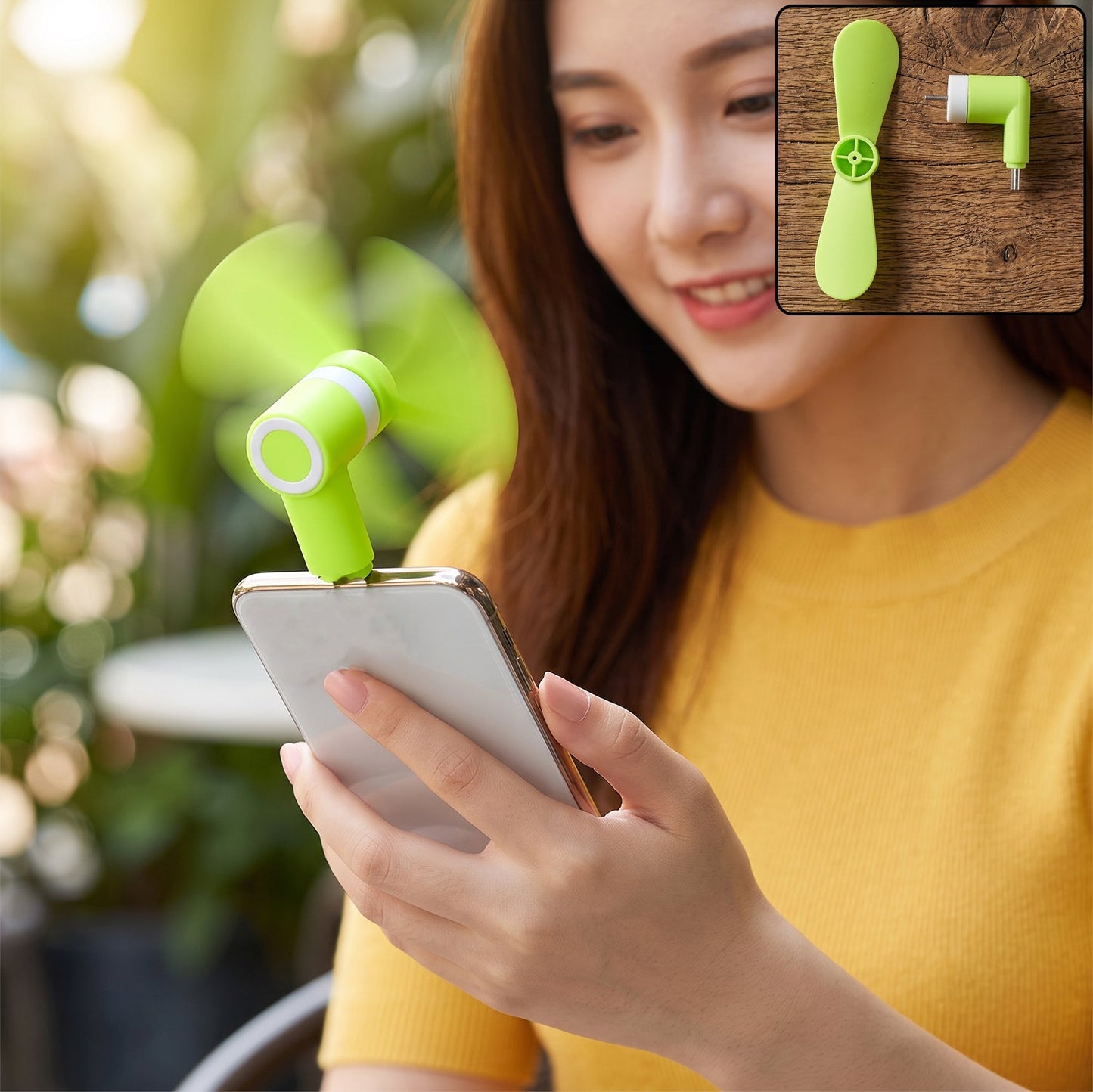 A woman holds a phone with a bright green USB-C fan plugged in, blowing air.