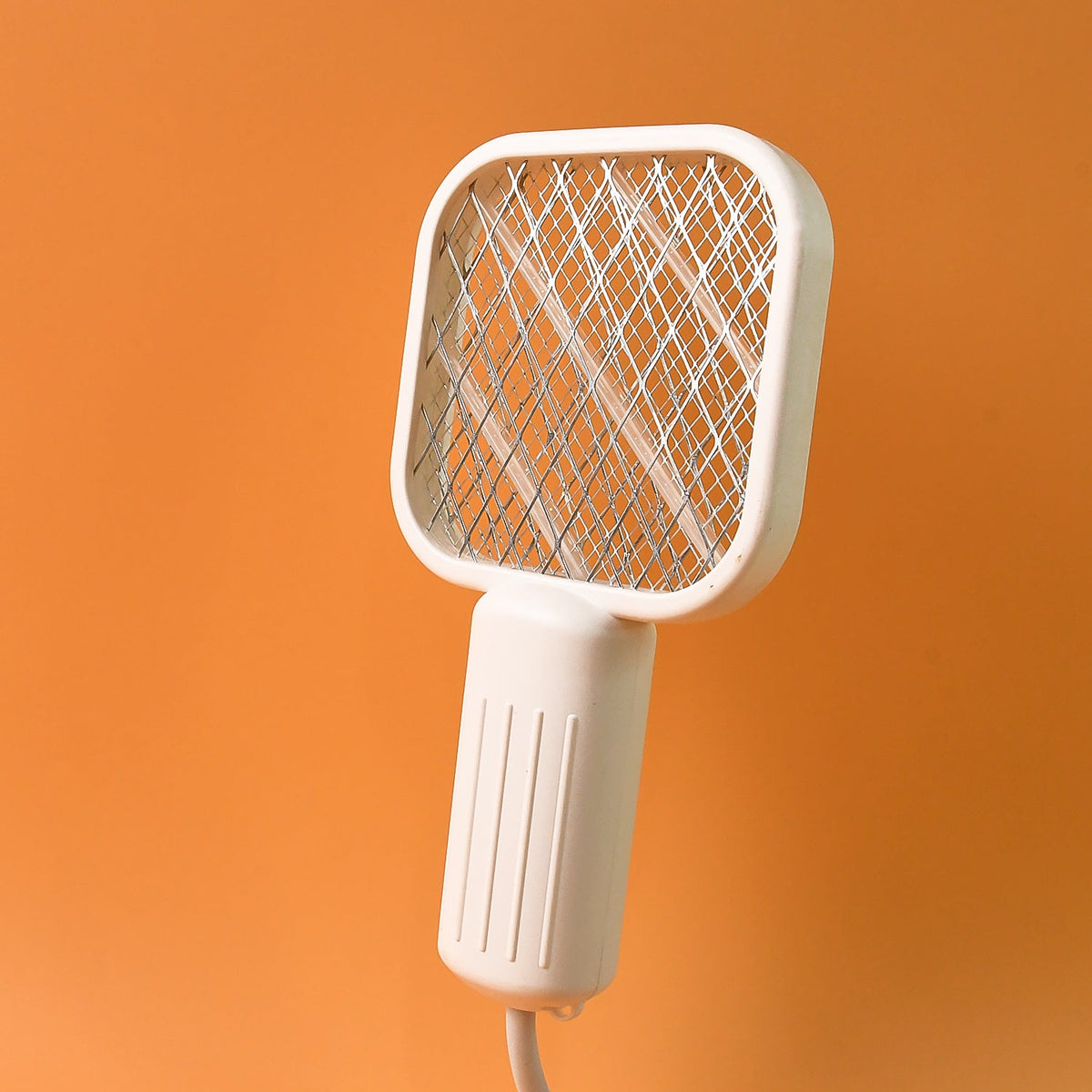 A white electric bug zapper with a square head and ribbed handle, on an orange background.