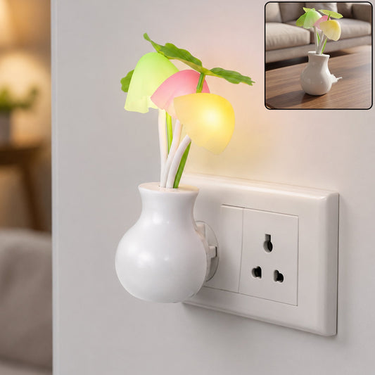 A white vase-shaped night light with glowing pink, yellow, and green mushroom-like lights plugged into a wall outlet. A