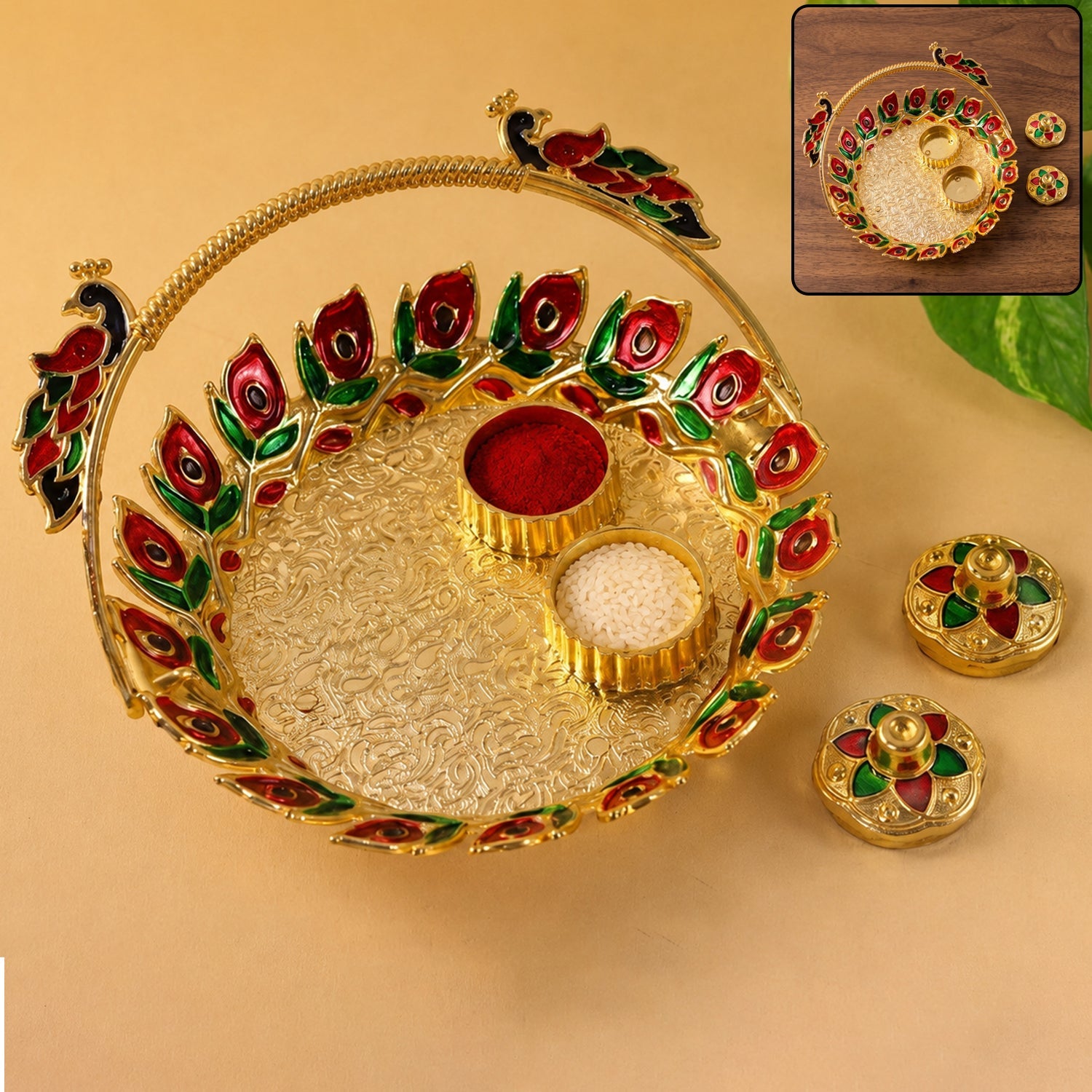 A golden kumkum dish with a peacock handle, holding red kumkum and white rice, with two matching lidded containers beside it.