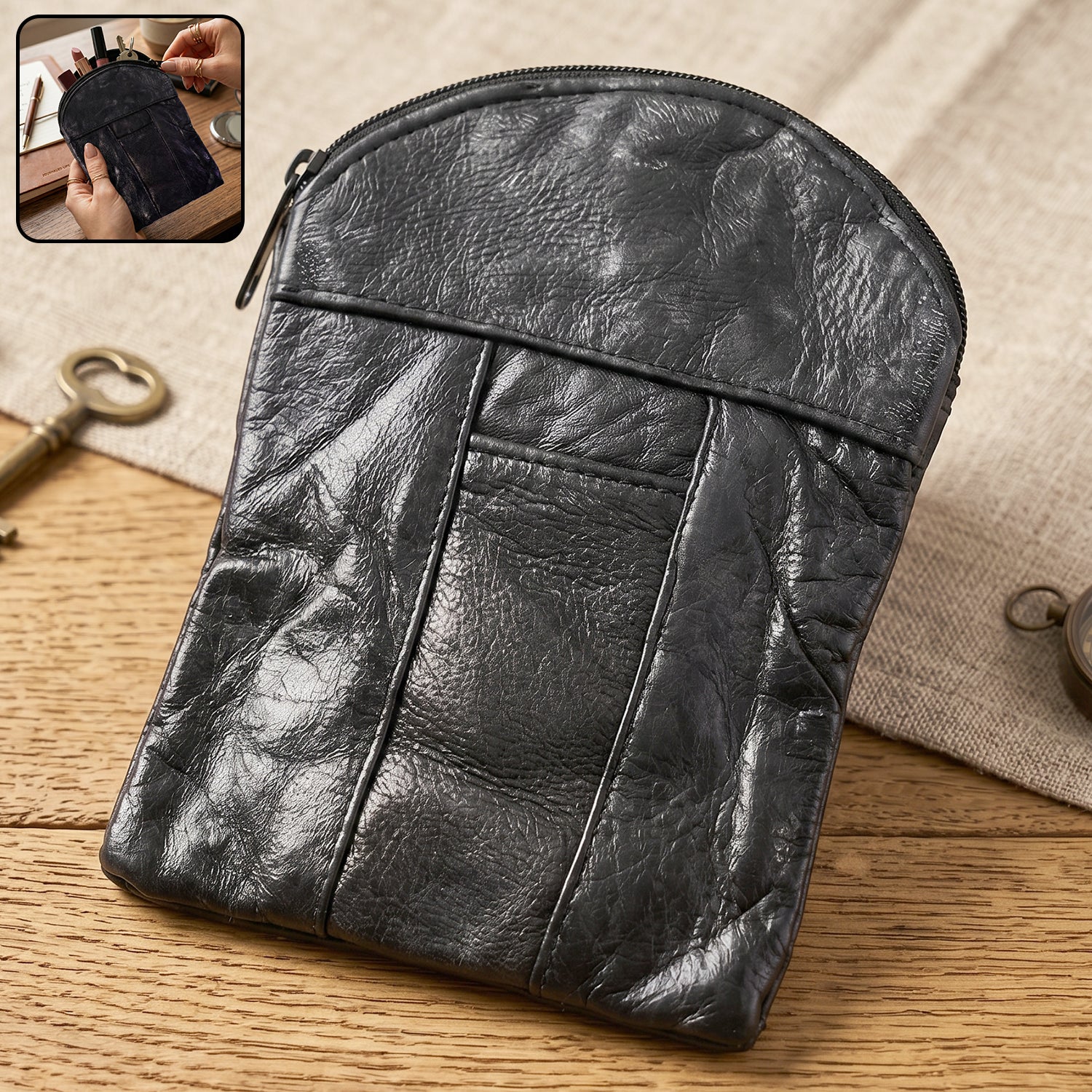 A black leather pouch with a zipper closure on a wooden surface, with a small inset showing it open.