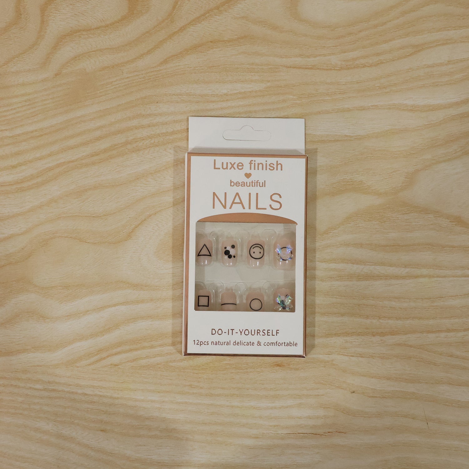 A white box of Luxe Finish Beautiful Nails, displaying 12 nude press-on nails with geometric designs and bows.