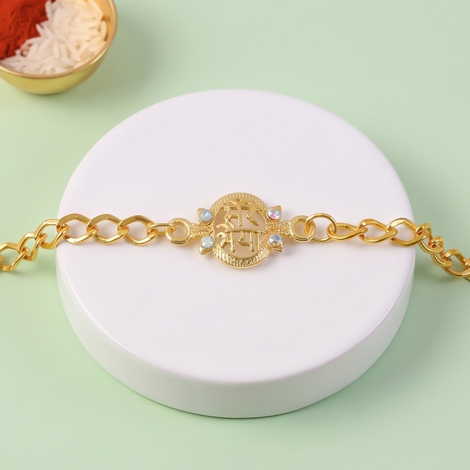 Mere Bhaiya gold-plated chain rakhi with stone embellishments displayed from above.