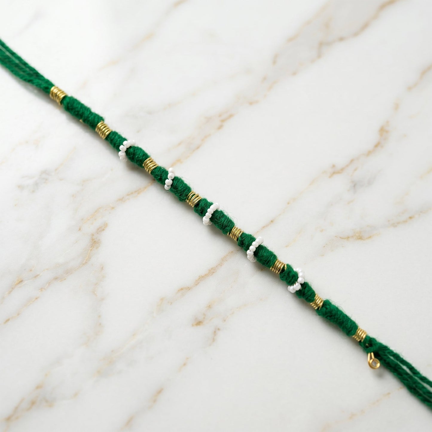 Traditional green rakhi showcasing pearl and golden bead accents