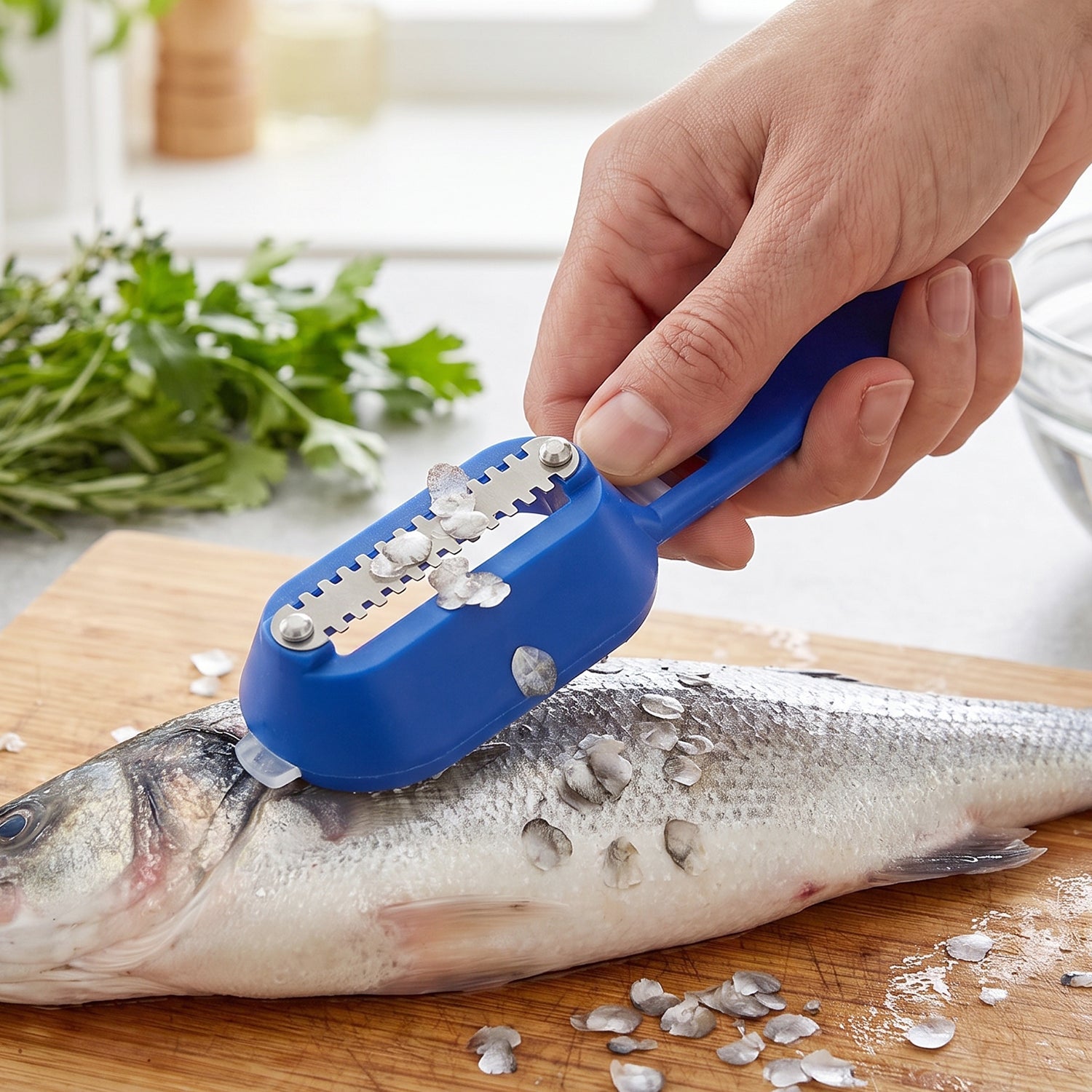 A blue fish scaler with a clear lid and a metal blade is shown on a wooden cutting board with a knife.