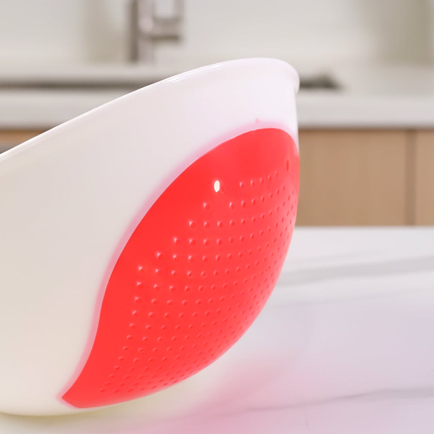 A close-up of the red perforated strainer section of the white whale-shaped bowl, showing its textured surface.