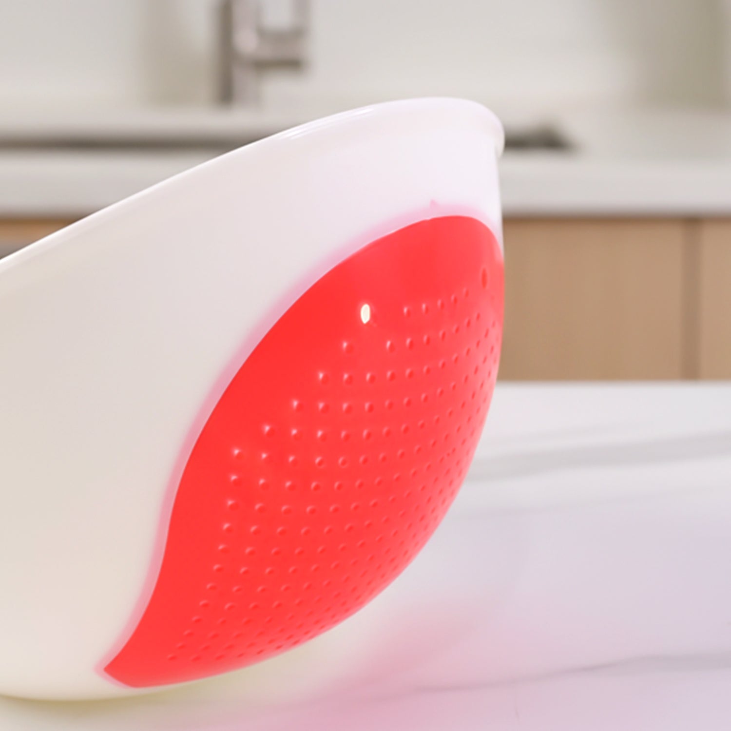 A close-up of the red perforated strainer section of the white whale-shaped bowl, showing its textured surface.