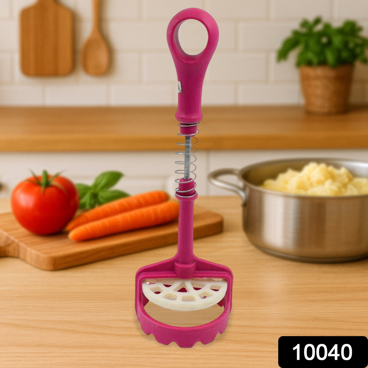 A pink and white plastic potato masher stands upright on a wooden counter with vegetables in the background.