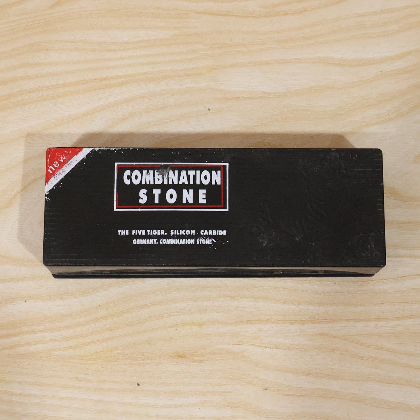 Black cardboard box with red and white text for "Combination Stone" on a light wooden surface.