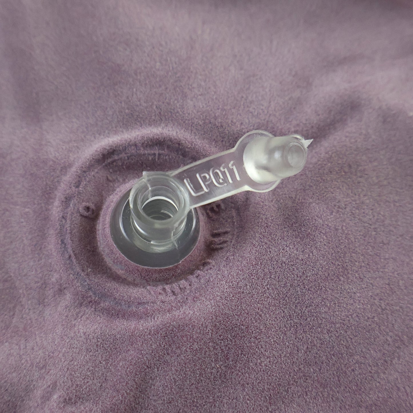 Close-up of the clear plastic inflation valve on the purple velvet U-shape neck pillow.